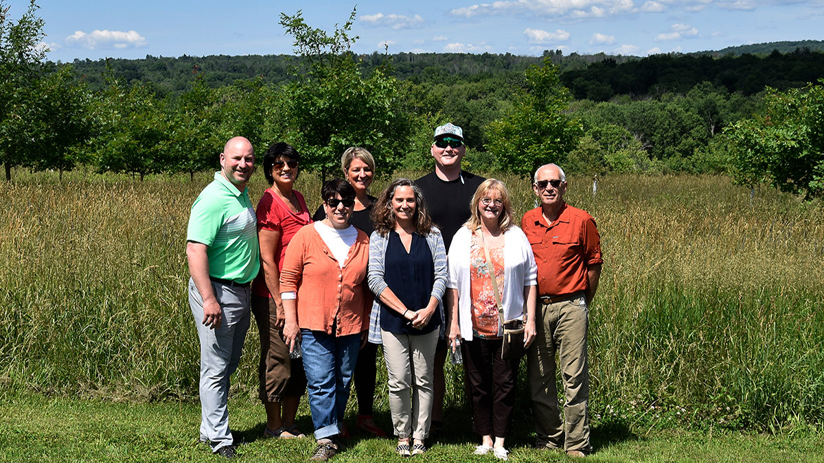 Conservancy director Diane Rosencrance stands with representatives from the Green Lodging Partnership in the meadow at the Van Scott Nature Reserve.