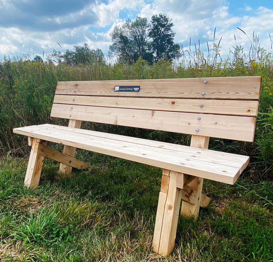 A wooden bench dedicated in memory of Ed Wesely.