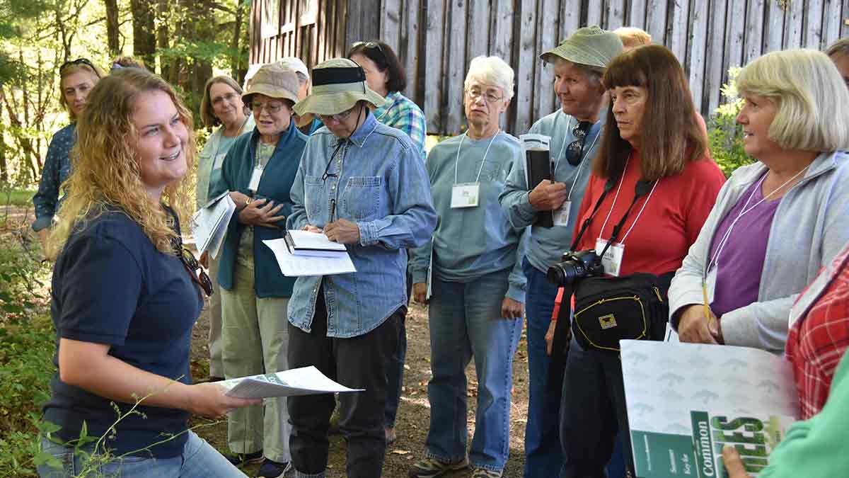 A group of attendees listen to a presenter at the Women and Their Woods workshop
