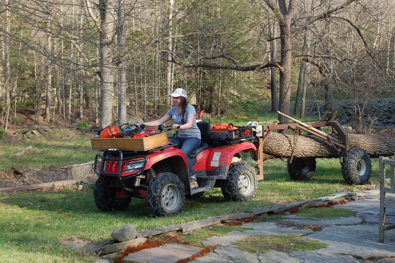 woman pulling a large log with tractor