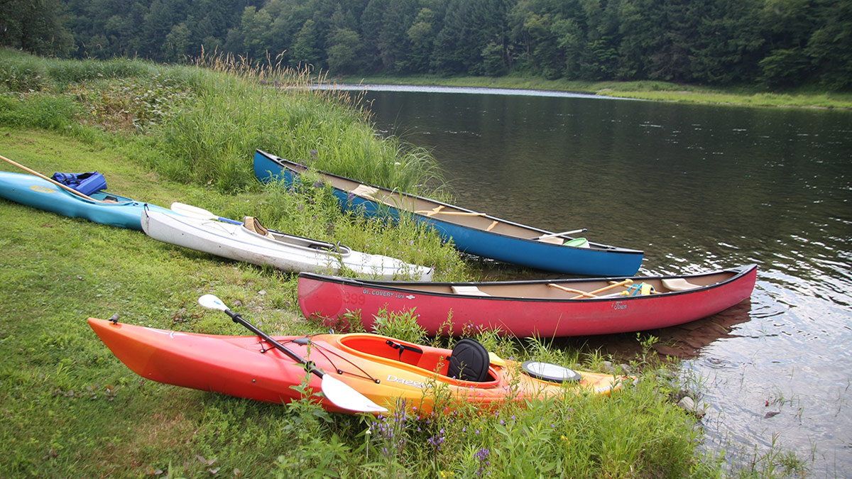 Colorful kayaks rest on the riverbank.