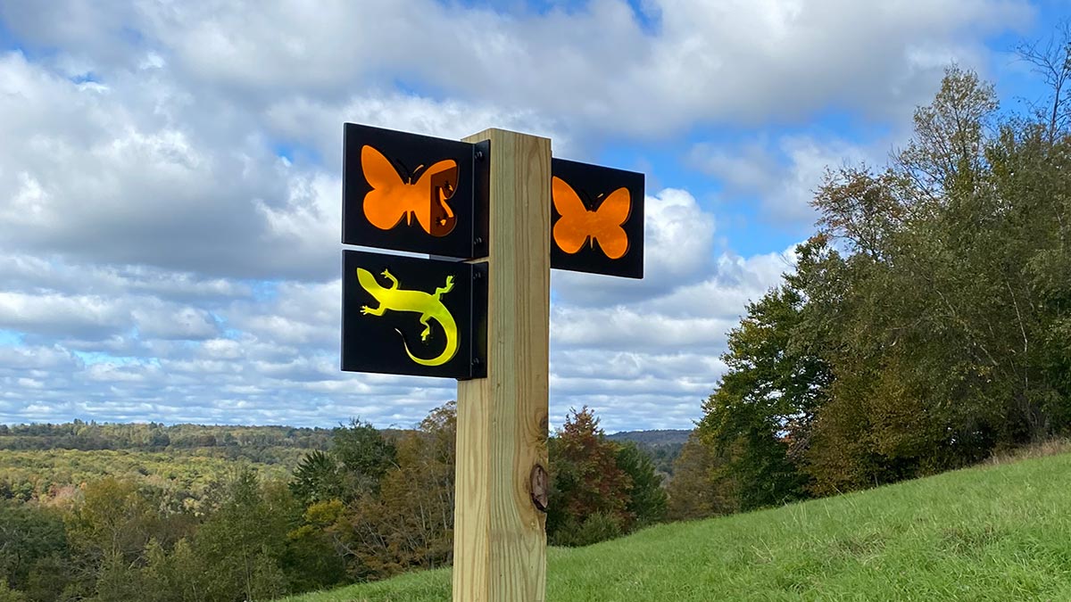 Trail signs at the Van Scott Nature Reserve with a scenic view over the neighboring hills.